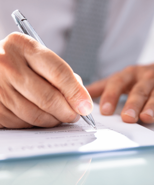 a man holding a silver pen signing paperwork