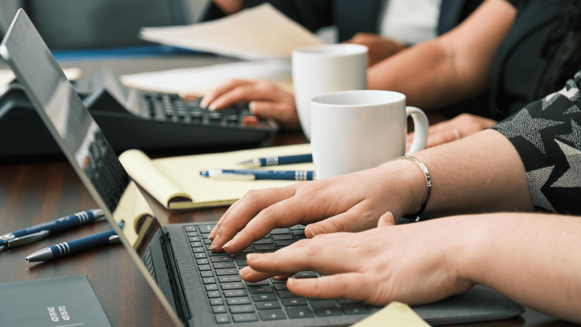 a closeup of a corporate team using laptops and drinking coffee