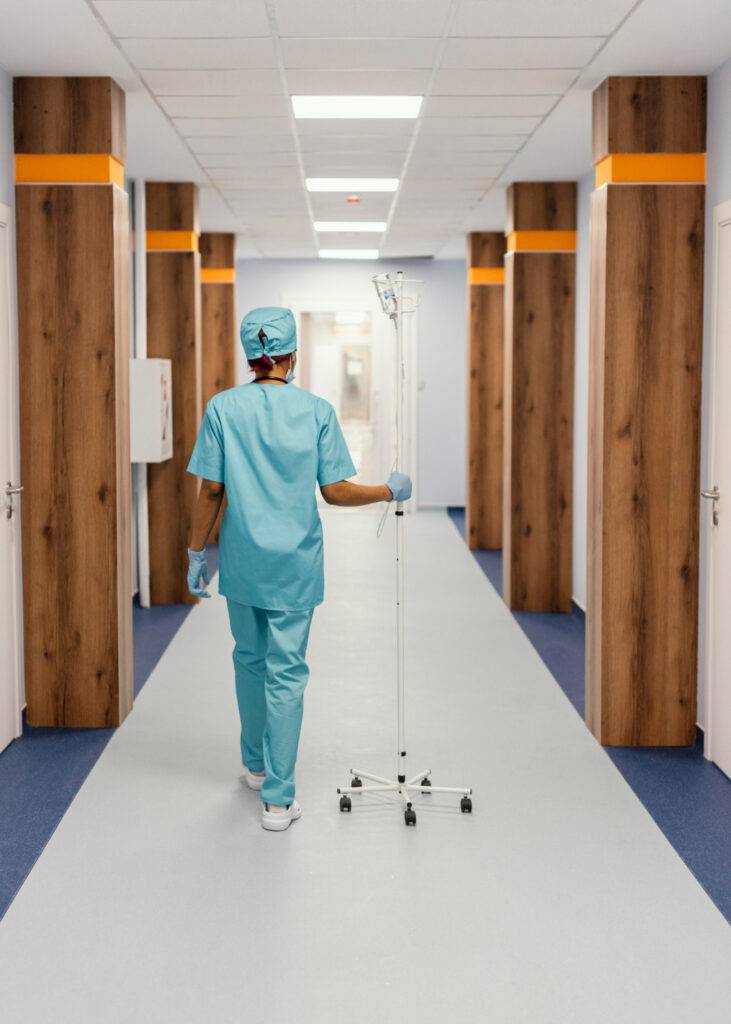 A nurse walking down a hospital hallway with healthcare equipment