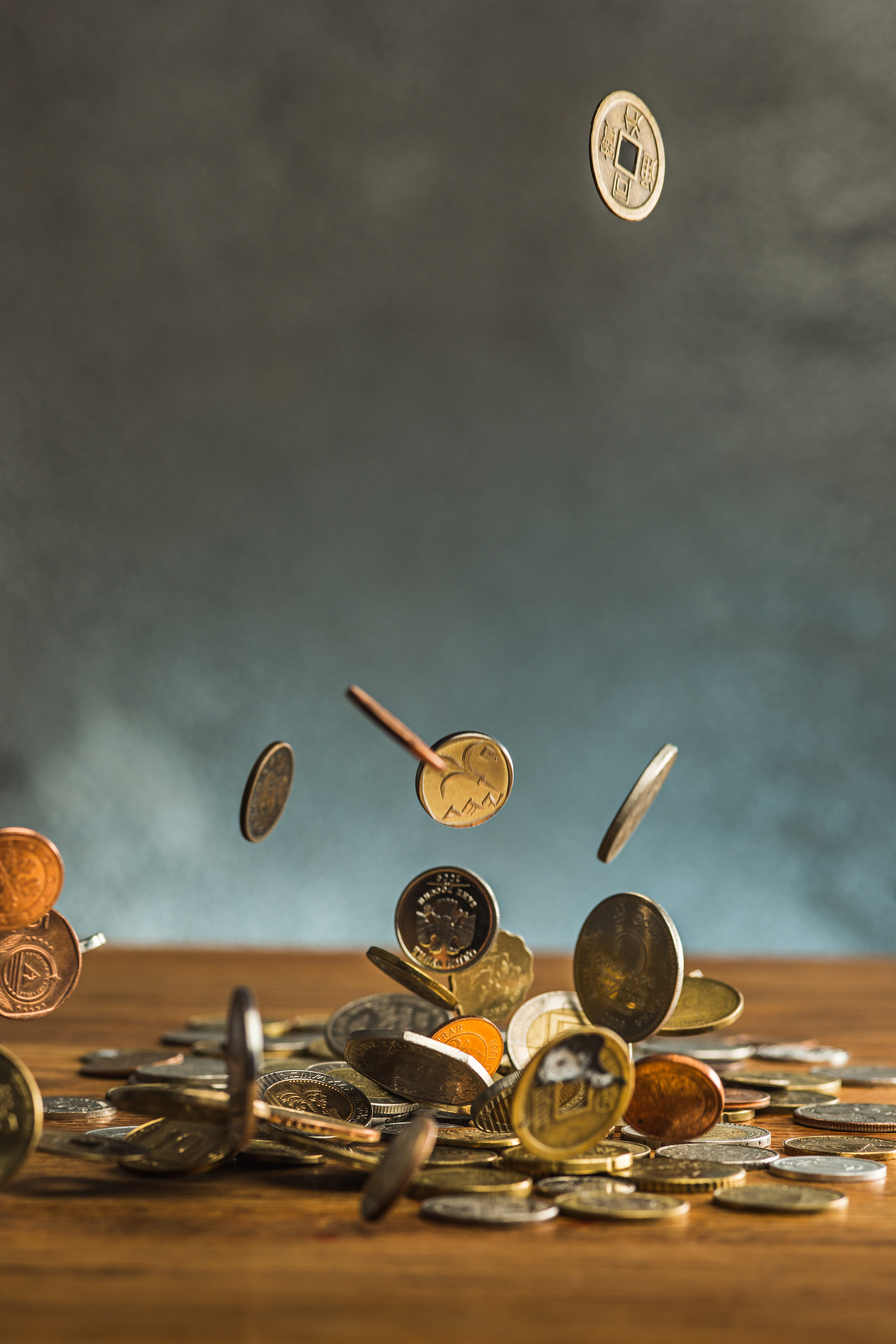 silver golden coins falling coins wooden wall