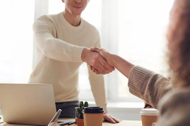 A man standing up to shake hands at an office table